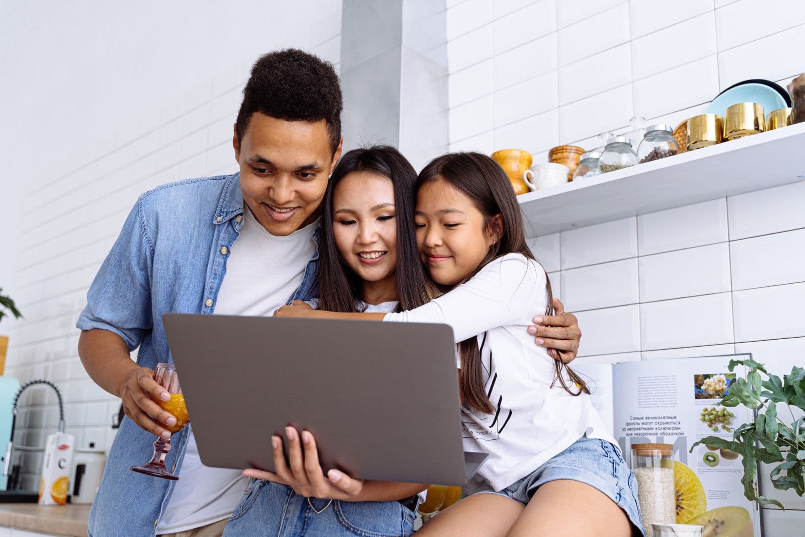 A joyful family of three gathered around a laptop in their bright kitchen, smiling as they read their child’s decoded plan together
